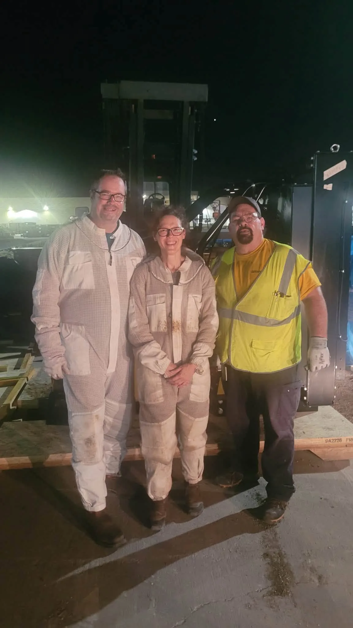Brad Bowdoin, at left in a beekeeping suit, with Chantel and a Caterpillar employee after a nighttime bee removal at Brad's workplace in Texas