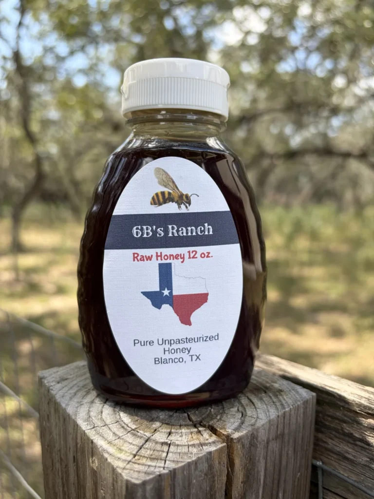 6B's Ranch 12 oz Blanco raw honey, dark amber, on a fence post