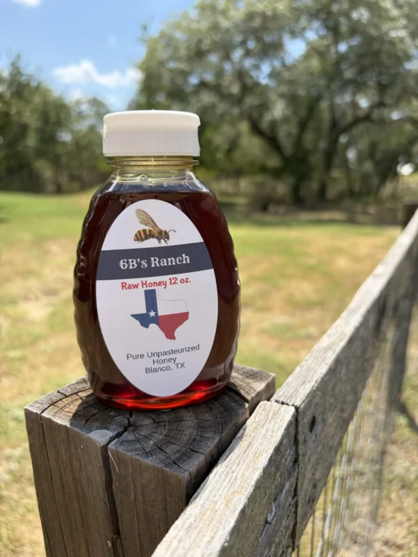 6B's Ranch 12 oz Blanco raw honey lit by afternoon sun on a fence rail